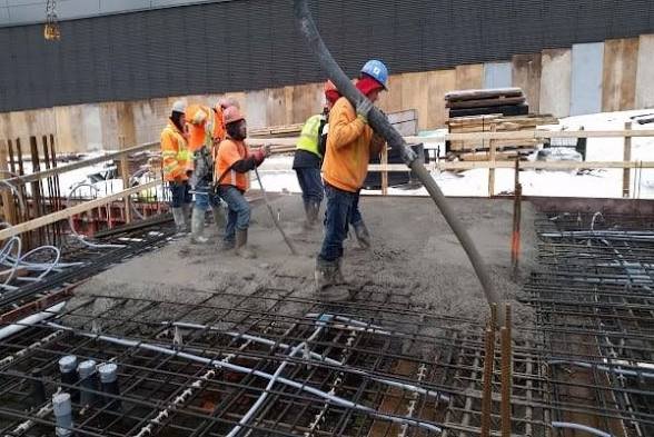 Concretagem de laje em andamento com equipe distribuindo o concreto bombeado